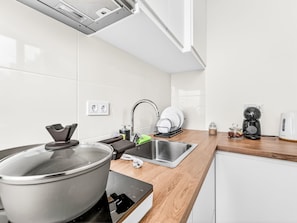 A modern kitchen with a stove, sink, and coffee maker. - Panoramic Studio View by Interhome (Funchal (Madeira))