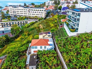 A residential area with modern buildings, a prominent house with a red roof, and lush greenery. - Panoramic Studio View by Interhome (Funchal (Madeira))
