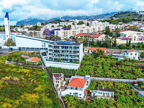 Un hotel modern amb diverses plantes, grans finestres i una terrassa al terrat.