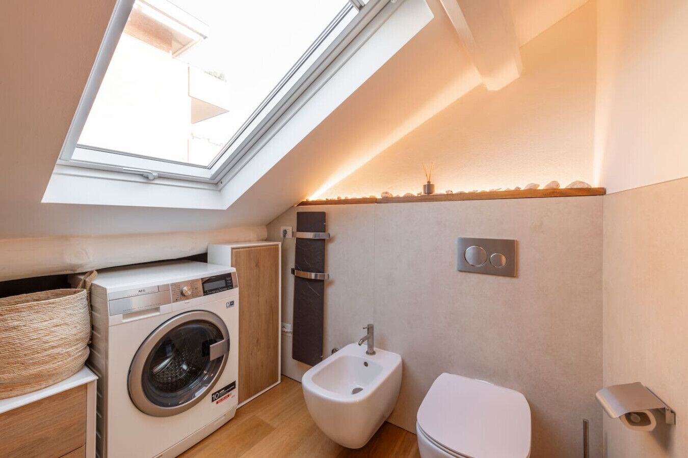Un bagno compatto con finestra a lucernario, lavatrice, bidet e WC.