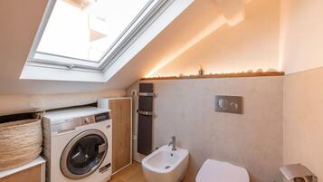 Un bagno compatto con finestra a lucernario, lavatrice, bidet e WC.
