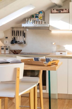 Cocina moderna con comedor, que incluye una mesa de madera, sillas y un colgador para utensilios.