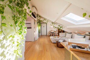 A modern loft apartment with a skylight, wooden flooring, a sofa, a dining area, and green plants. - Bright Attic Penthouse Safe Central Clean Quiet (Milano)