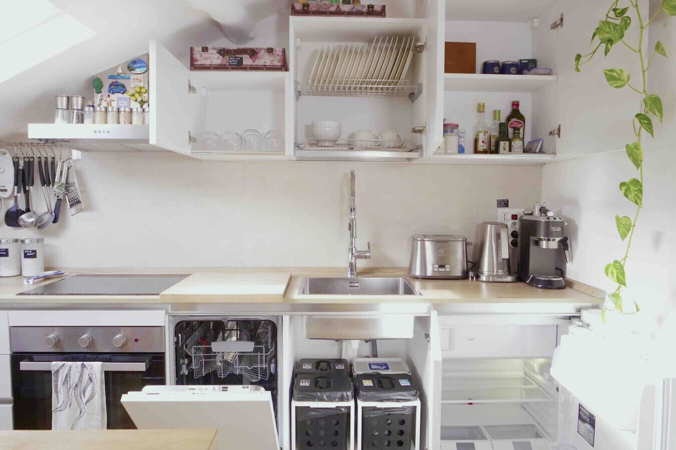 Una cucina compatta con lavastoviglie, fornello e macchina da caffè.