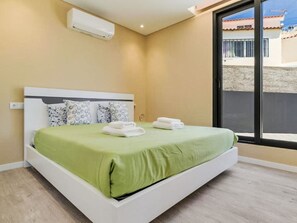 Ein Schlafzimmer mit Bett, Kissen, einem Fenster und einer Klimaanlage.