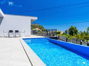 Ein Schwimmbad mit einem weißen Gebäude und Stühlen im Hintergrund.