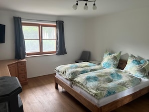 A bedroom with a wooden bed, a desk, a chair, and a window with curtains. - Seehuber Vacation Rental (Siegsdorf)