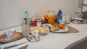 A breakfast table with various food items, drinks, and a coffee maker.