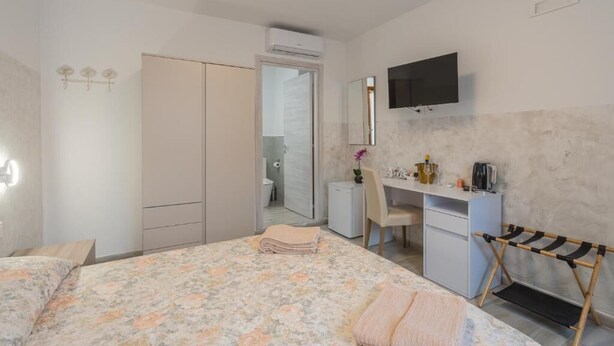 Une chambre à coucher comprenant un lit, un bureau, une chaise, un téléviseur et une armoire.