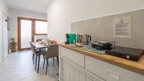 Une cuisine compacte comprenant un coin repas, une machine à café, une bouilloire et un petit réfrigérateur.