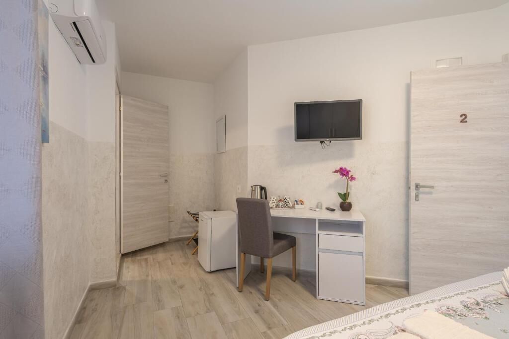 A bedroom with a bed, a desk, a chair, a television, and a door with a number.