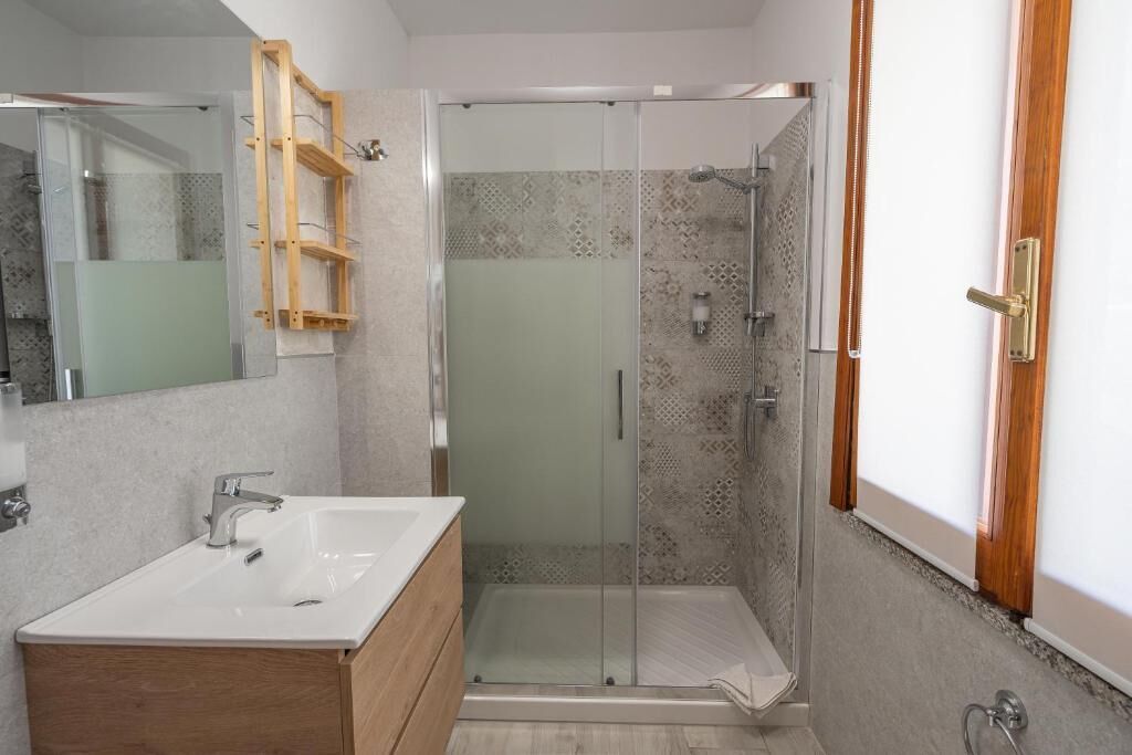 Un baño moderno con cabina de ducha de vidrio, tocador de madera y un espejo grande.
