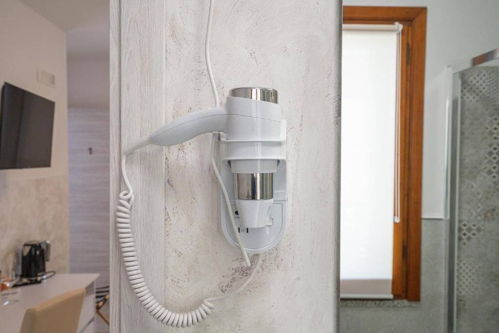 Un teléfono fijo de pared con cable, un televisor de pantalla plana montado en la pared y una puerta con marco de madera.
