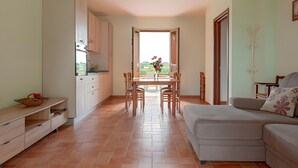 Una cucina moderna con zona pranzo, un divano e vista attraverso un'apertura.