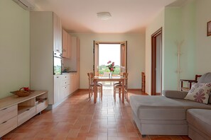 Eine moderne Küche mit Essbereich, einer Couch und Blick durch eine offene Tür.