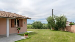 Una casa con tetto in tegole, un piccolo giardino e una recinzione.