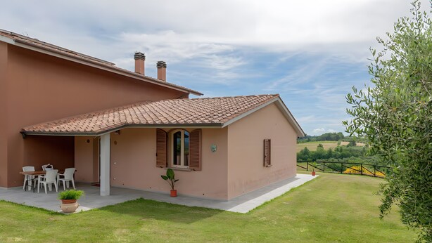 Una casa con patio, zona pranzo e giardino.