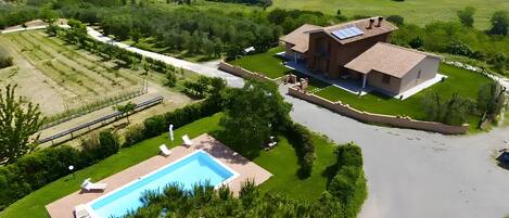 Una propiedad residencial con piscina, jardín y panel solar en el techo.