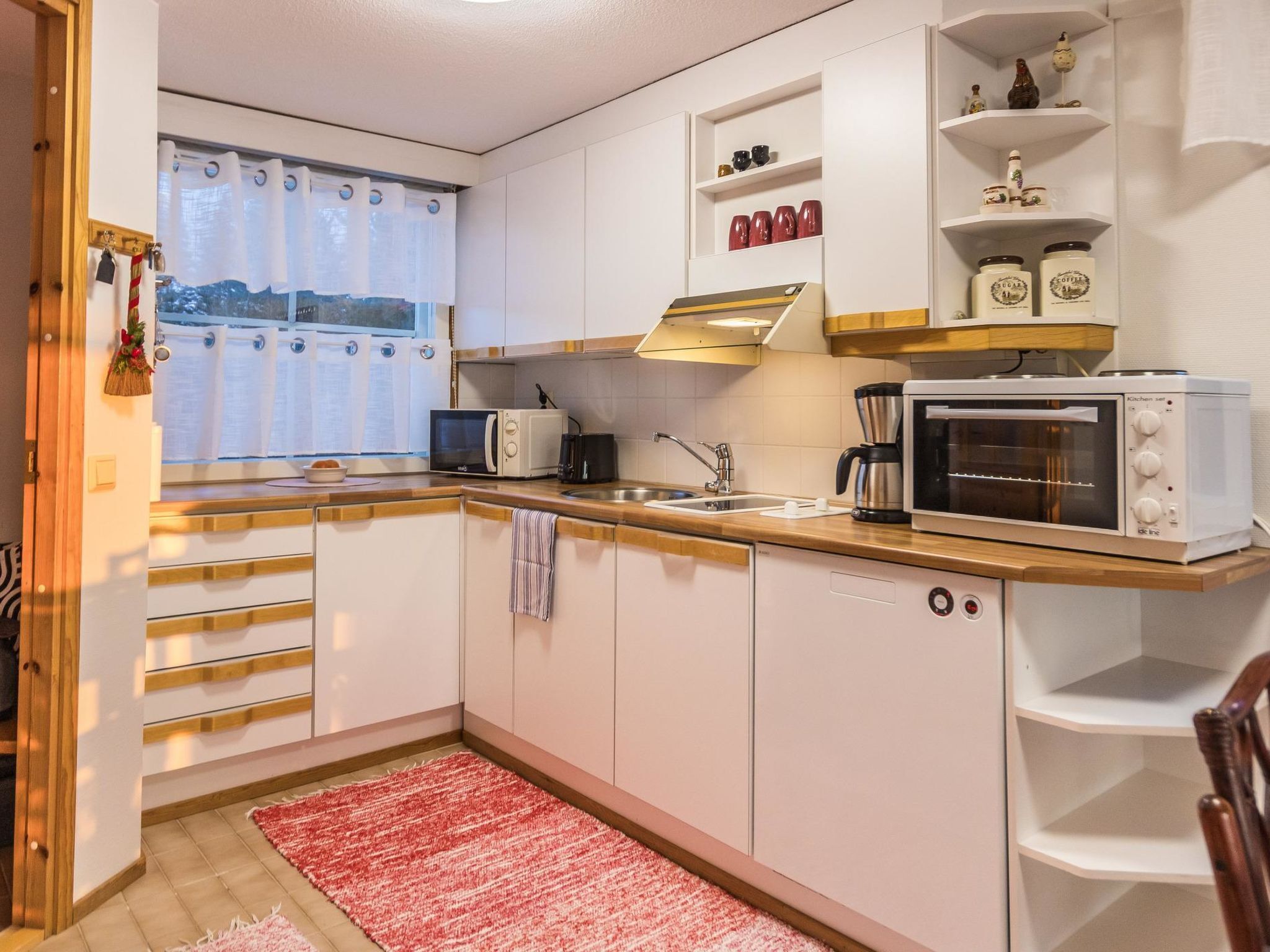 A compact kitchen with white cabinets, a microwave, a coffee maker, and a toaster oven.