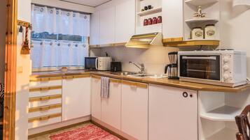 A compact kitchen with white cabinets, a microwave, a coffee maker, and a toaster oven.