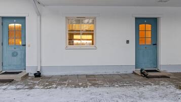 A white building with two blue doors, numbered 15 and 16, and a window between them.