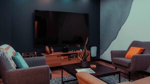 A modern living room with a flat-screen TV, two armchairs, a coffee table, and a wooden cabinet. - Student Only YourTRIBE Southwark (London)