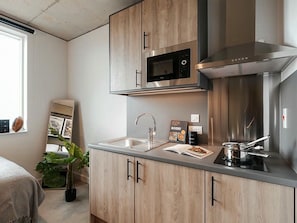 Eine moderne Küche mit Holzausstattung, einer Edelstahl-Mikrowelle, einer Spüle und einem Herd.
