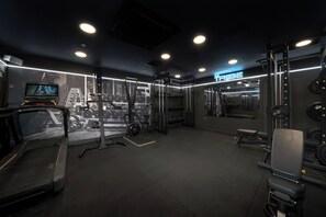 Ein modernes Fitnessstudio mit verschiedenen Trainingsgeräten, darunter Laufbänder, Kraftgeräte und Kurzhanteln.