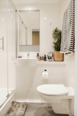 Ein modernes Badezimmer mit Duschkabine aus Glas, einem weißen Waschbecken und einer Toilette.