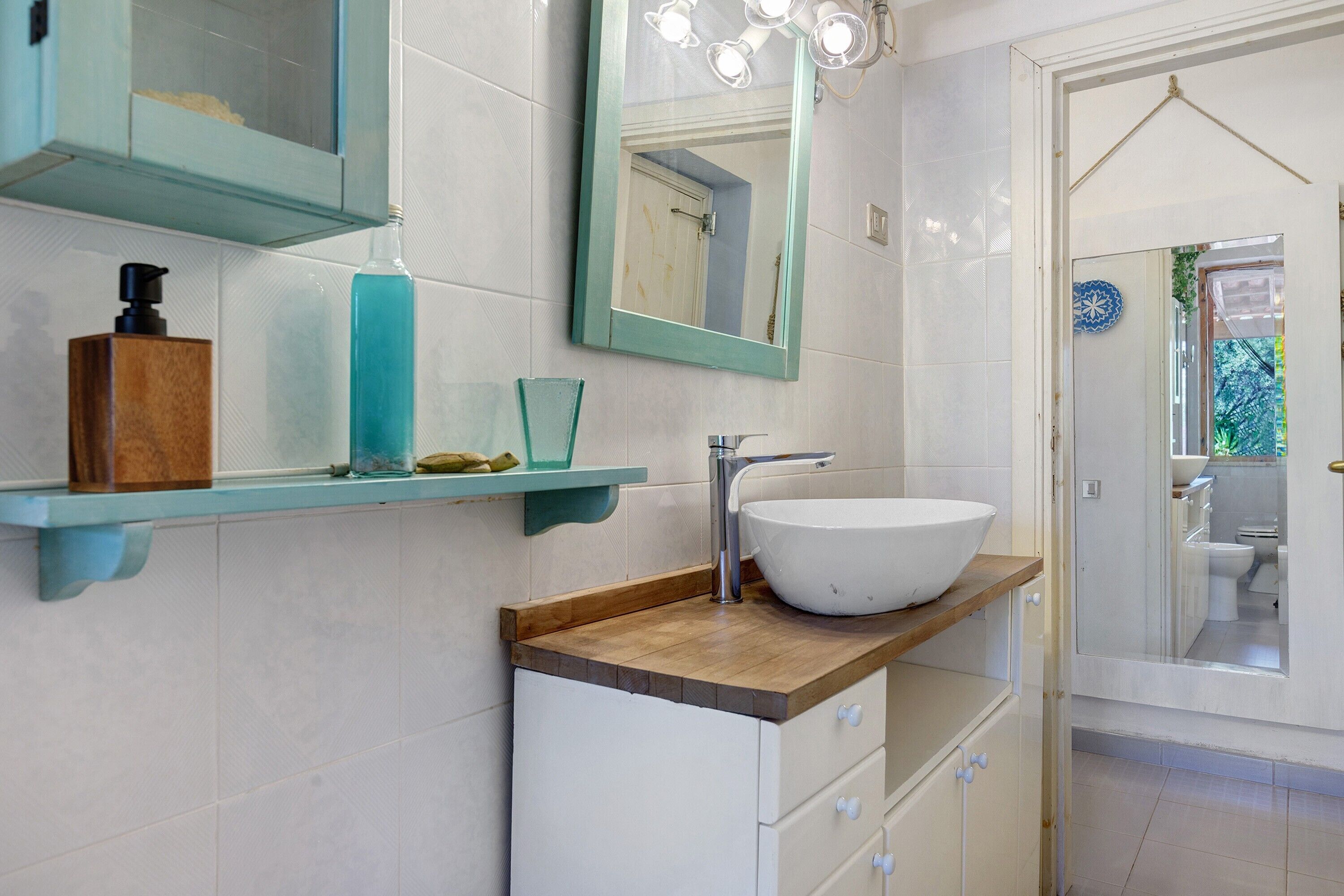 A bathroom with a white sink, a mirror, and a wooden countertop.