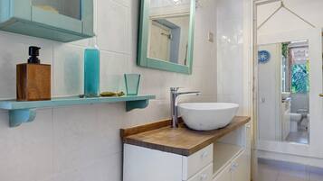 A bathroom with a white sink, a mirror, and a wooden countertop.