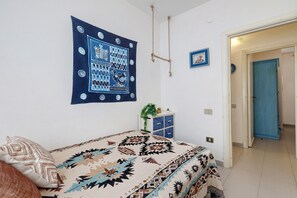 Ein Schlafzimmer mit einem Bett, einer Wandteppich, einem kleinen Schrank und einer Tür.