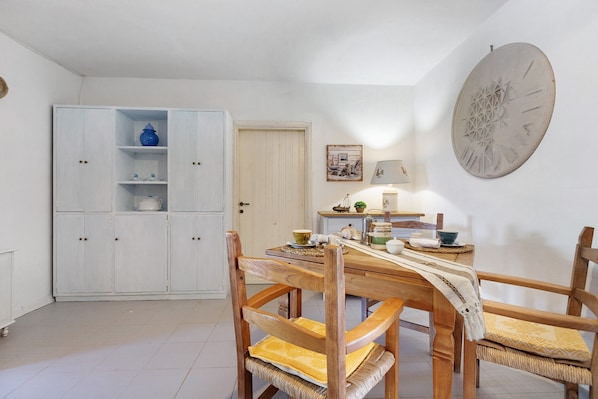 A dining area with a wooden table, chairs, and a white cabinet with shelves.