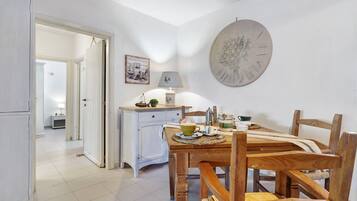 Uma sala de jantar com uma mesa de madeira, cadeiras, um abajur e um prato decorativo fixado na parede.