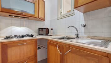 Una cucina con mobili in legno, un forno a microonde, un fornello a gas e un lavello.