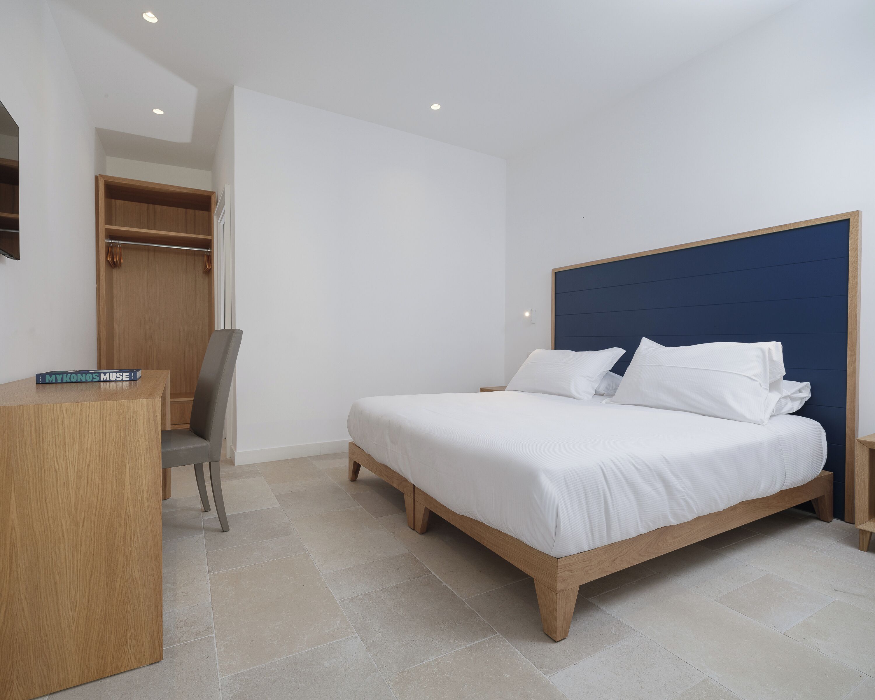 A bedroom with a bed, a desk, a chair, and a wardrobe.