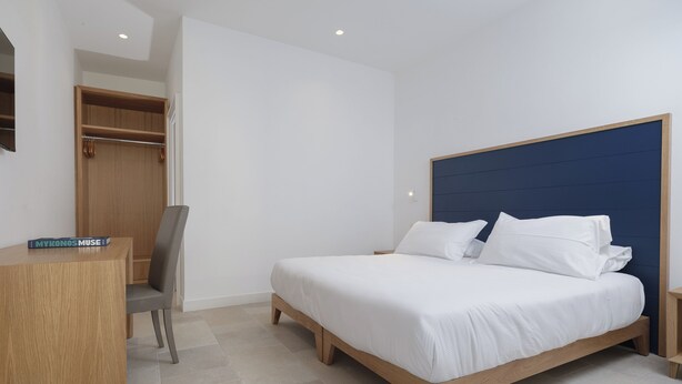 Een slaapkamer met een bed, bureau, stoel en kledingkast.