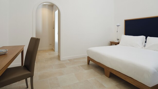 Una habitación de hotel con cama, escritorio y una silla.