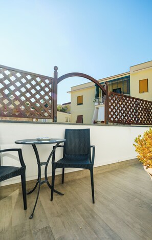 Un patio al aire libre con una mesa y dos sillas, una valla de madera y un edificio al fondo.