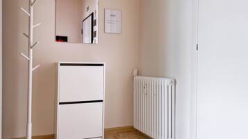 A room with a white radiator, a white stand-alone heater, and a coat rack.