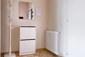 Ein Zimmer mit einem weißen Heizkörper, einem separaten weißen Heizgerät und einem Kleiderständer.