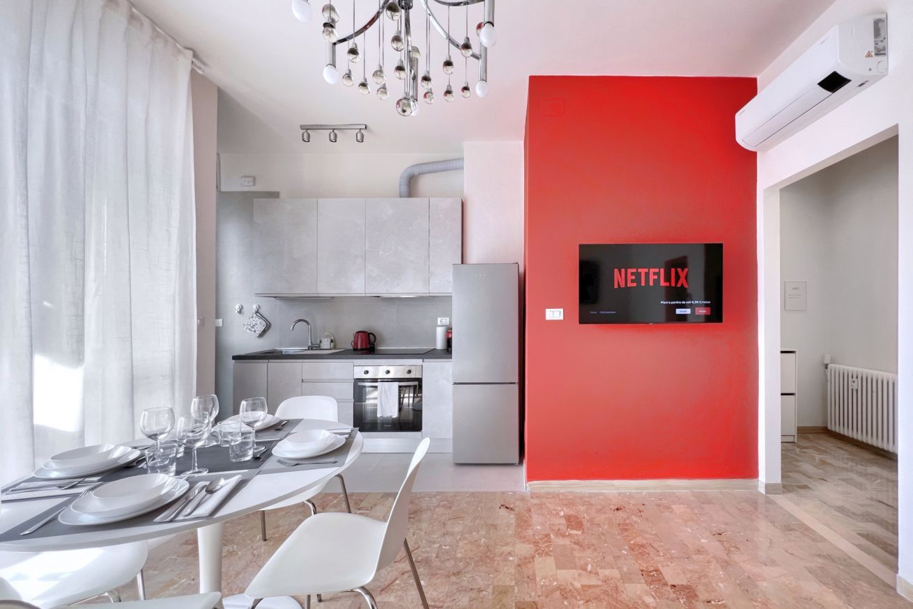 Una cucina moderna con forno integrato e una parete decorata di rosso.