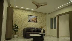 Una sala de estar moderna con piso de mármol, un sofá, una mesa redonda de centro, un ventilador de techo y un cuadro en la pared.