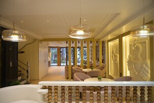 A modern interior with a seating area, a staircase, and a hallway leading to an outdoor space.