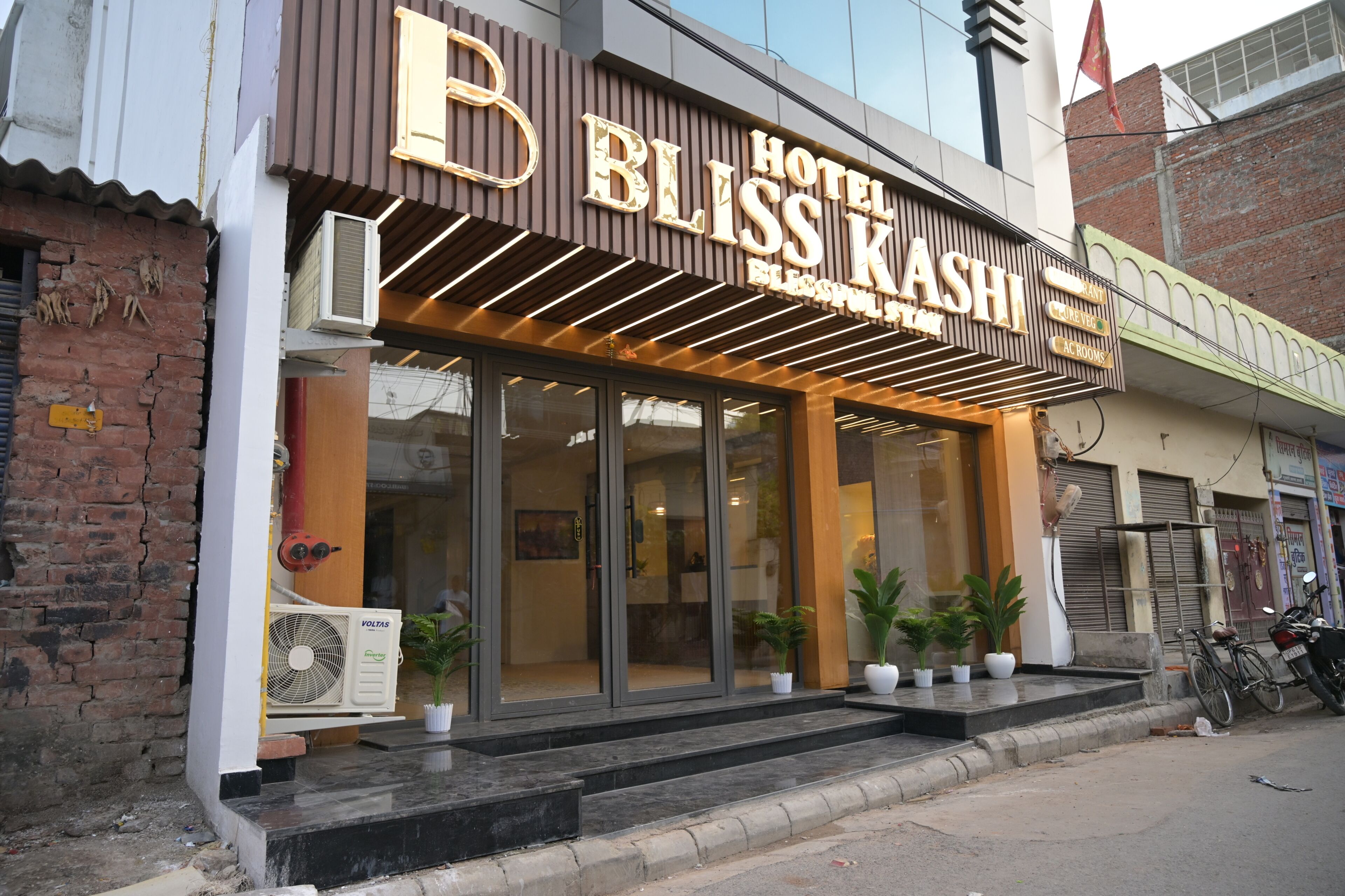 A hotel with a modern facade, large glass windows, and a sign that reads 'BLOSS KASHI HOTEL'.