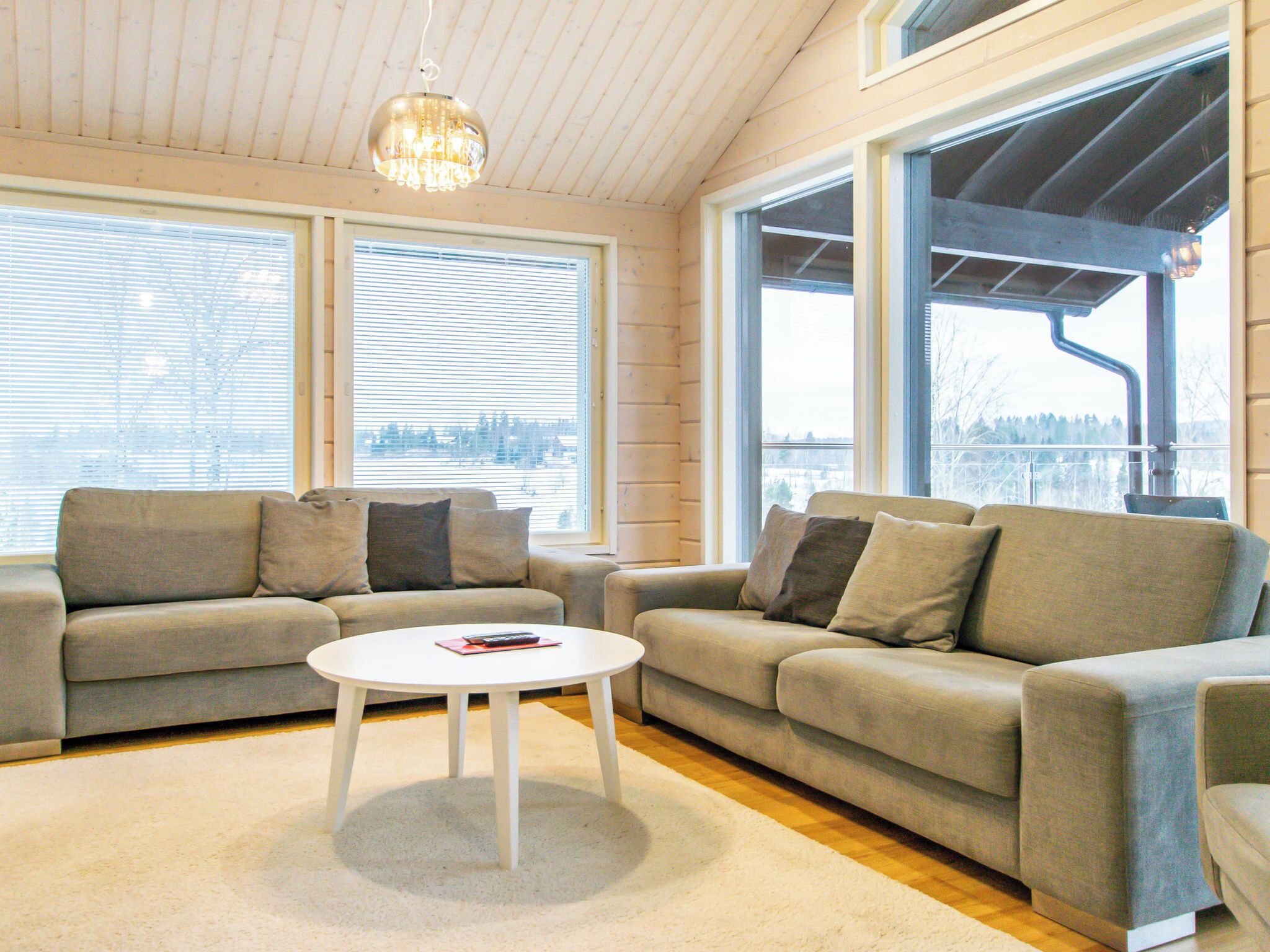 A modern living room with two sofas, a coffee table, and large windows providing a view of the outdoors.