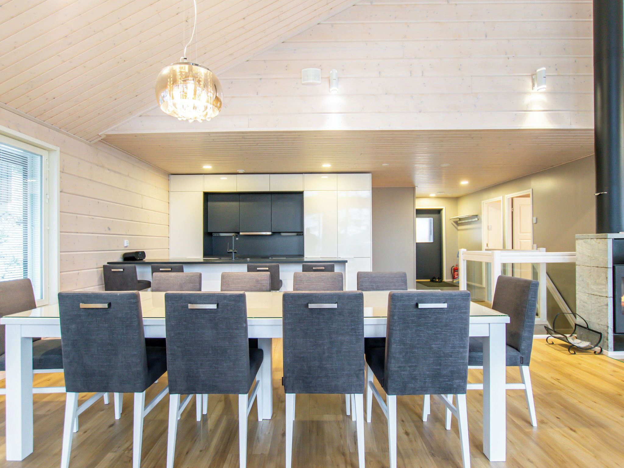 Een moderne keuken met witte kasten, een centraal eiland en een eetgedeelte met een witte tafel en grijze stoelen.