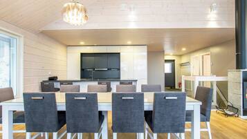 Een moderne keuken met witte kasten, een centraal eiland en een eetgedeelte met een witte tafel en grijze stoelen.