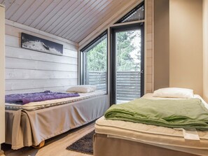 Un dormitorio con dos camas, techo de madera, ventana con persianas y un cuadro en la pared.