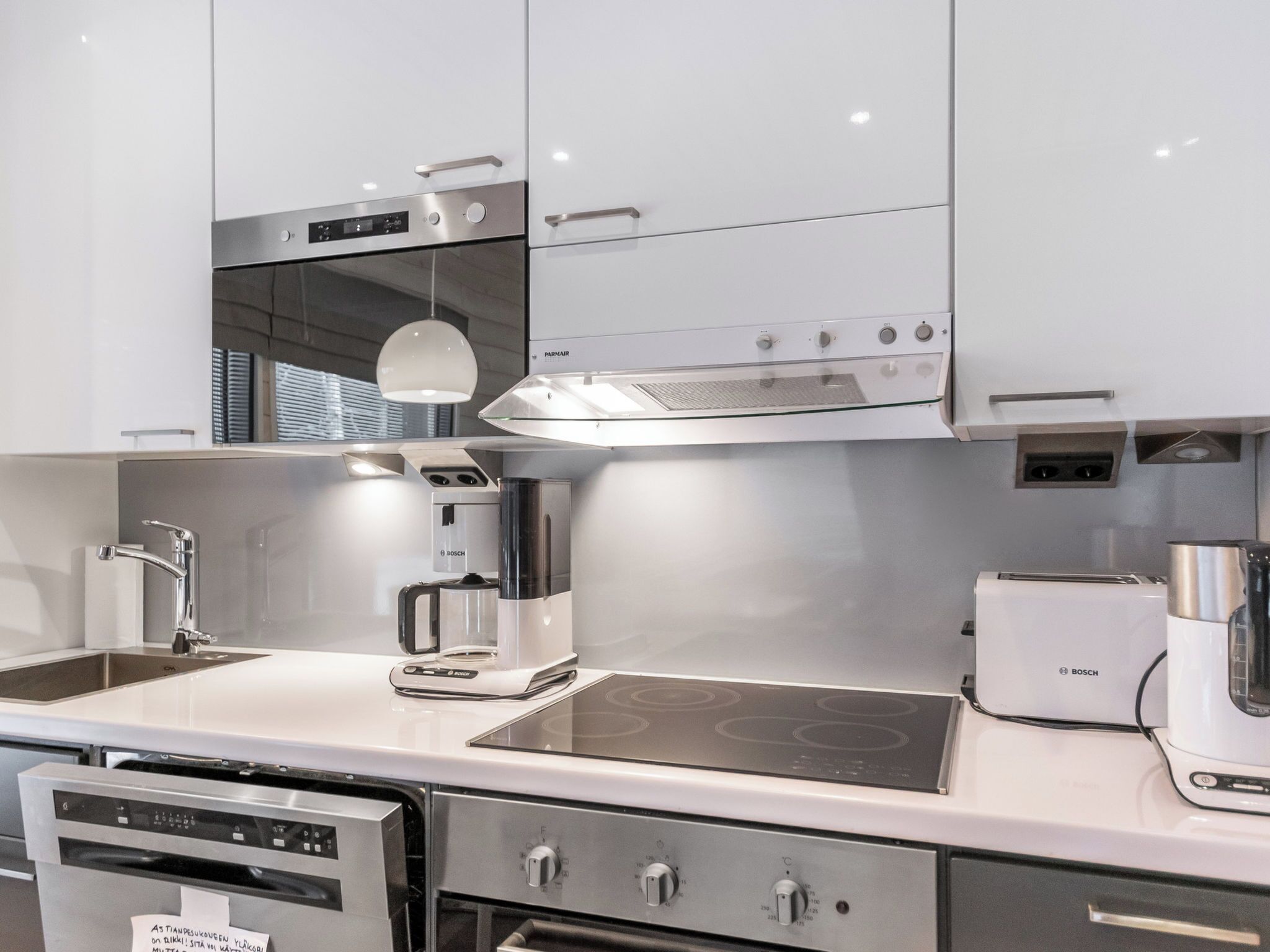 A modern kitchen with stainless steel appliances, a Bosch coffee maker, and a dishwasher.
